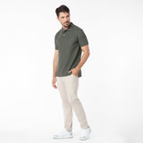 Man wearing a green polo shirt and beige pants on a white background