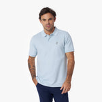Man wearing a light blue polo shirt with a brand logo on a white background