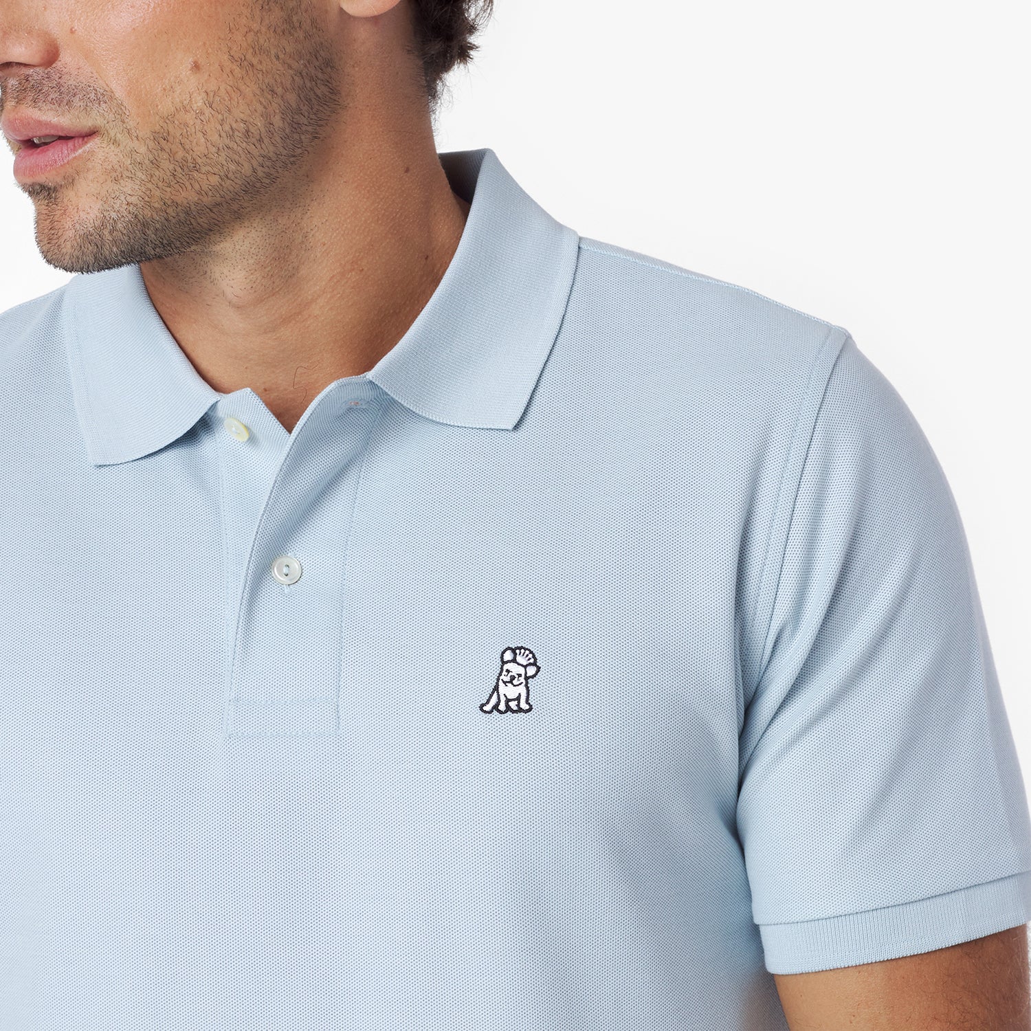 Close-up of a light blue polo shirt with a small logo on a white background