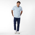 Man wearing a light blue polo shirt and navy pants on a white background