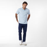 Man wearing a light blue polo shirt and navy pants on a white background