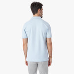 Back view of a man wearing a light blue polo shirt on a white background