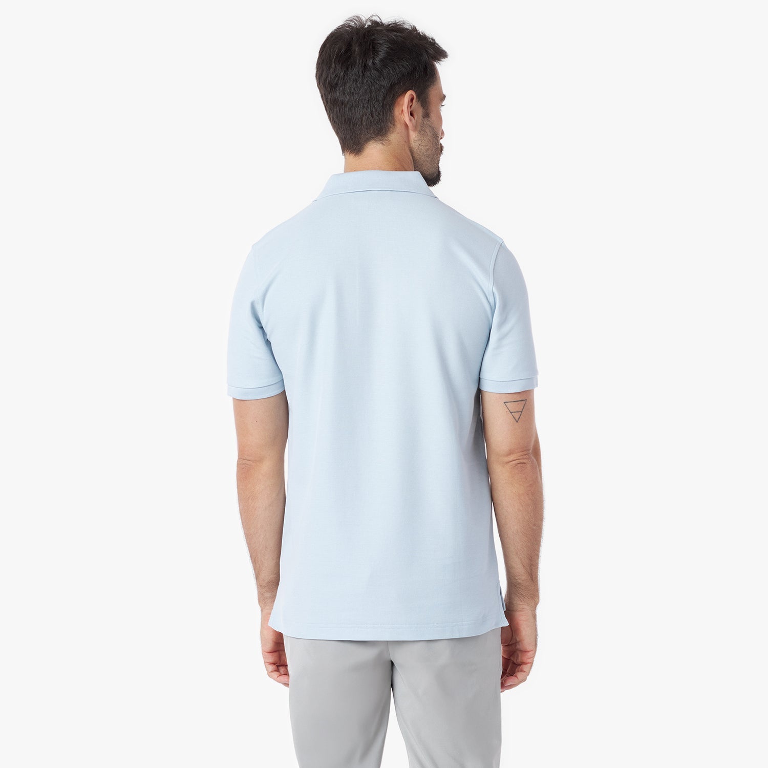 Back view of a man wearing a light blue polo shirt on a white background