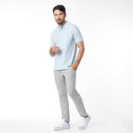Man wearing a light blue polo shirt and gray pants on a white background