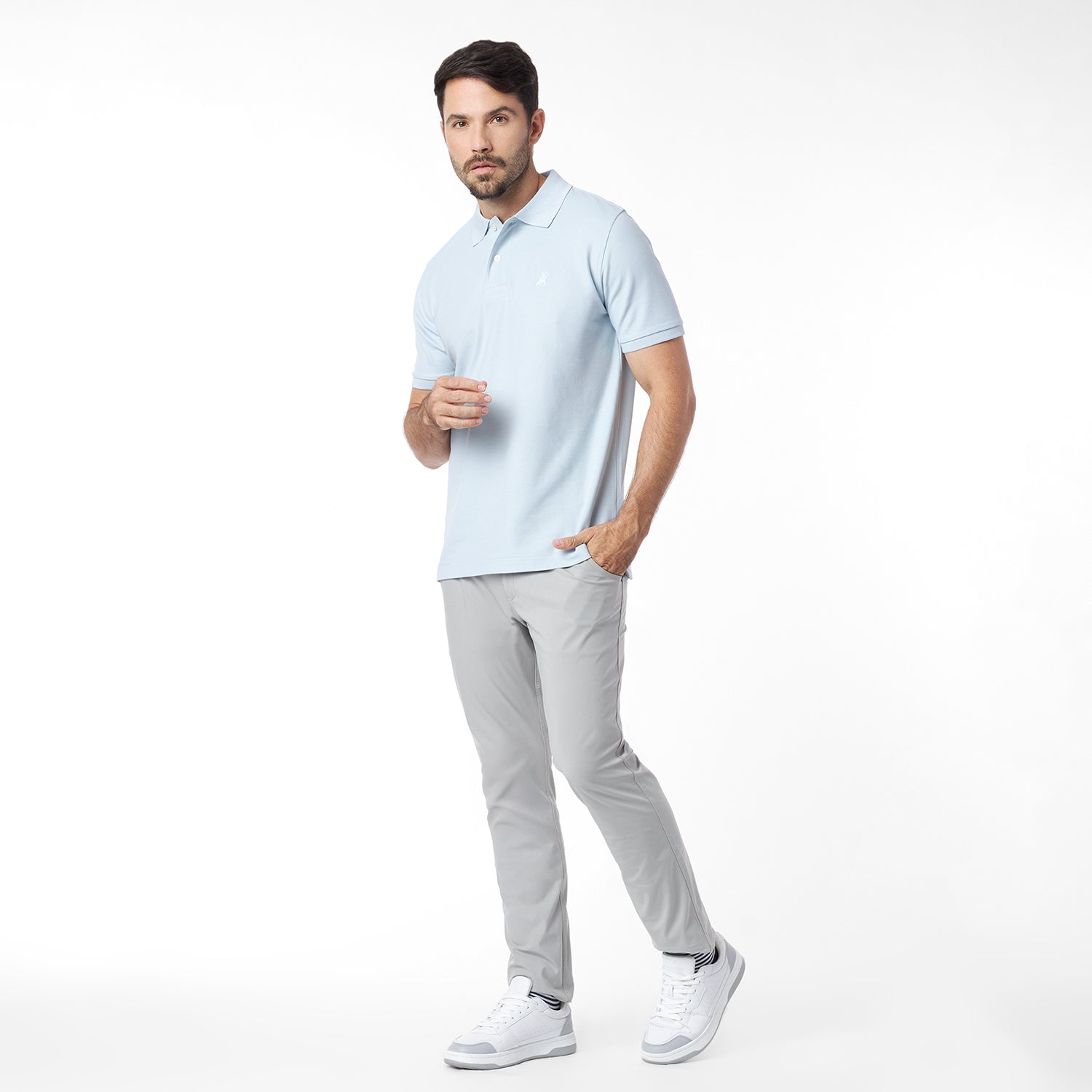 Man wearing a light blue polo shirt and gray pants on a white background