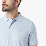 Close-up of a light blue polo shirt with a small logo on a white background
