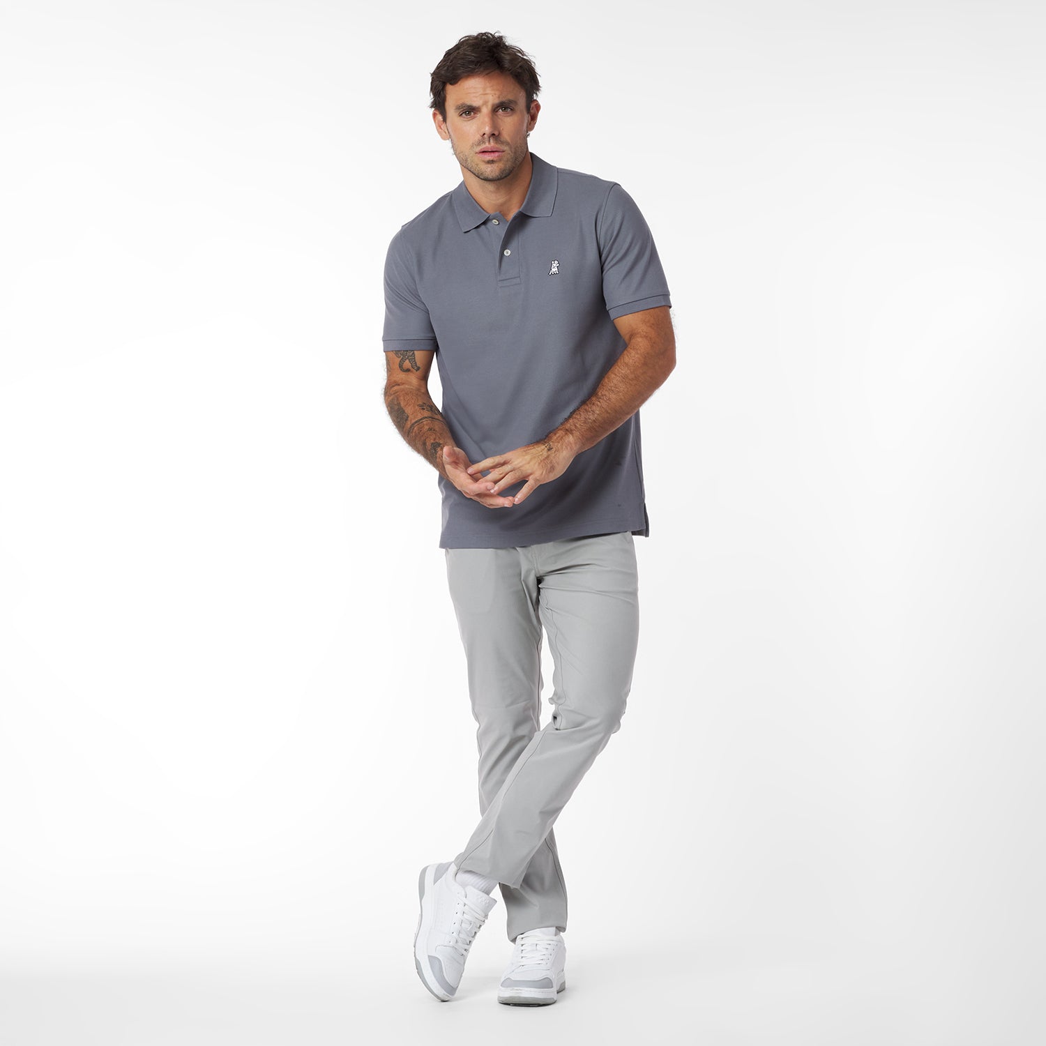 Man wearing a gray polo shirt and light gray pants on a white background