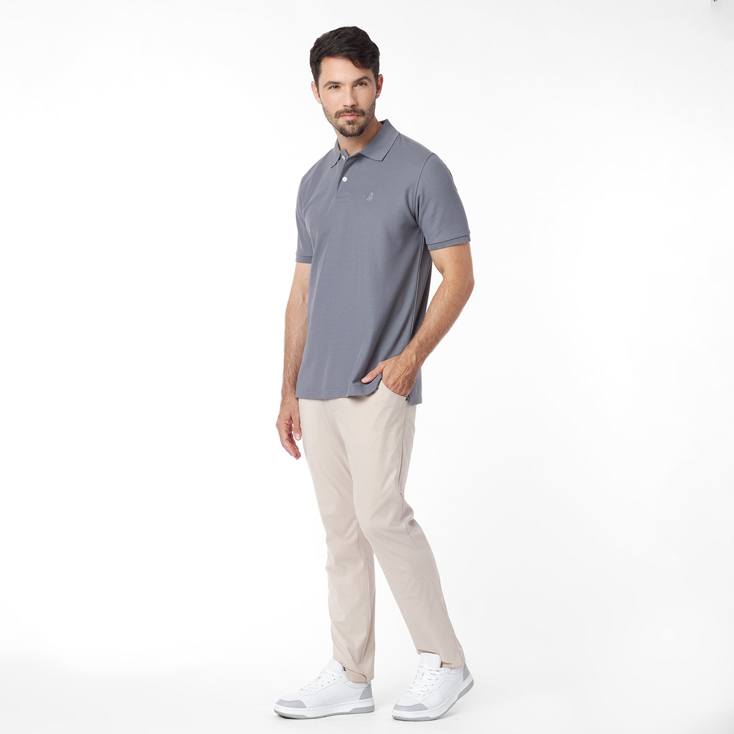 Man wearing a gray polo shirt and beige pants on a white background