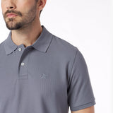 Close-up of a man wearing a gray polo shirt with a small logo on a white background