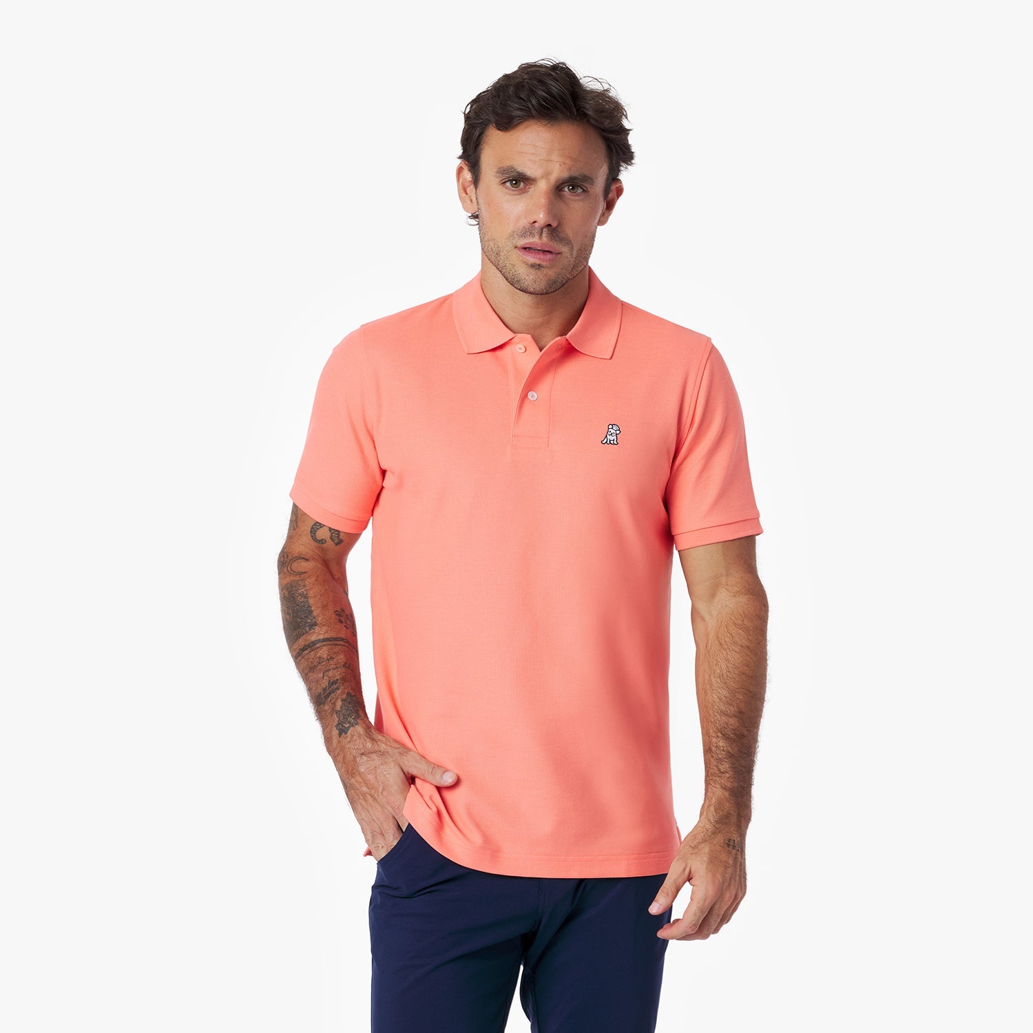 Man wearing a coral polo shirt with a small logo on a white background