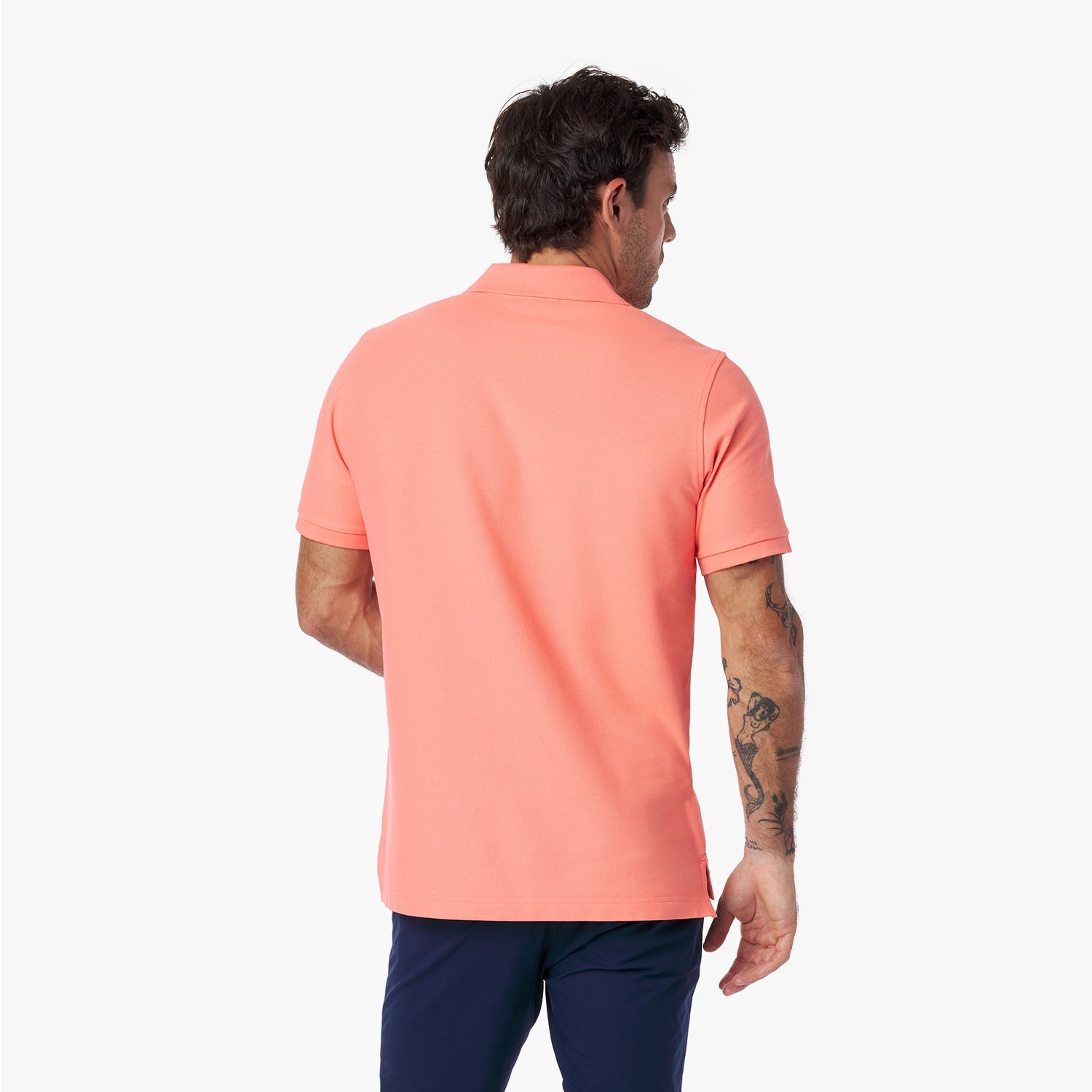 Back view of a man wearing a coral polo shirt on a white background