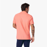 Back view of a man wearing a coral polo shirt on a white background