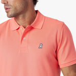 Close-up of a coral polo shirt with a small logo on a white background