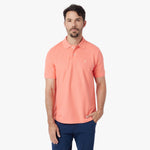 Man wearing a coral polo shirt on a white background