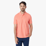 Man wearing a coral polo shirt on a white background