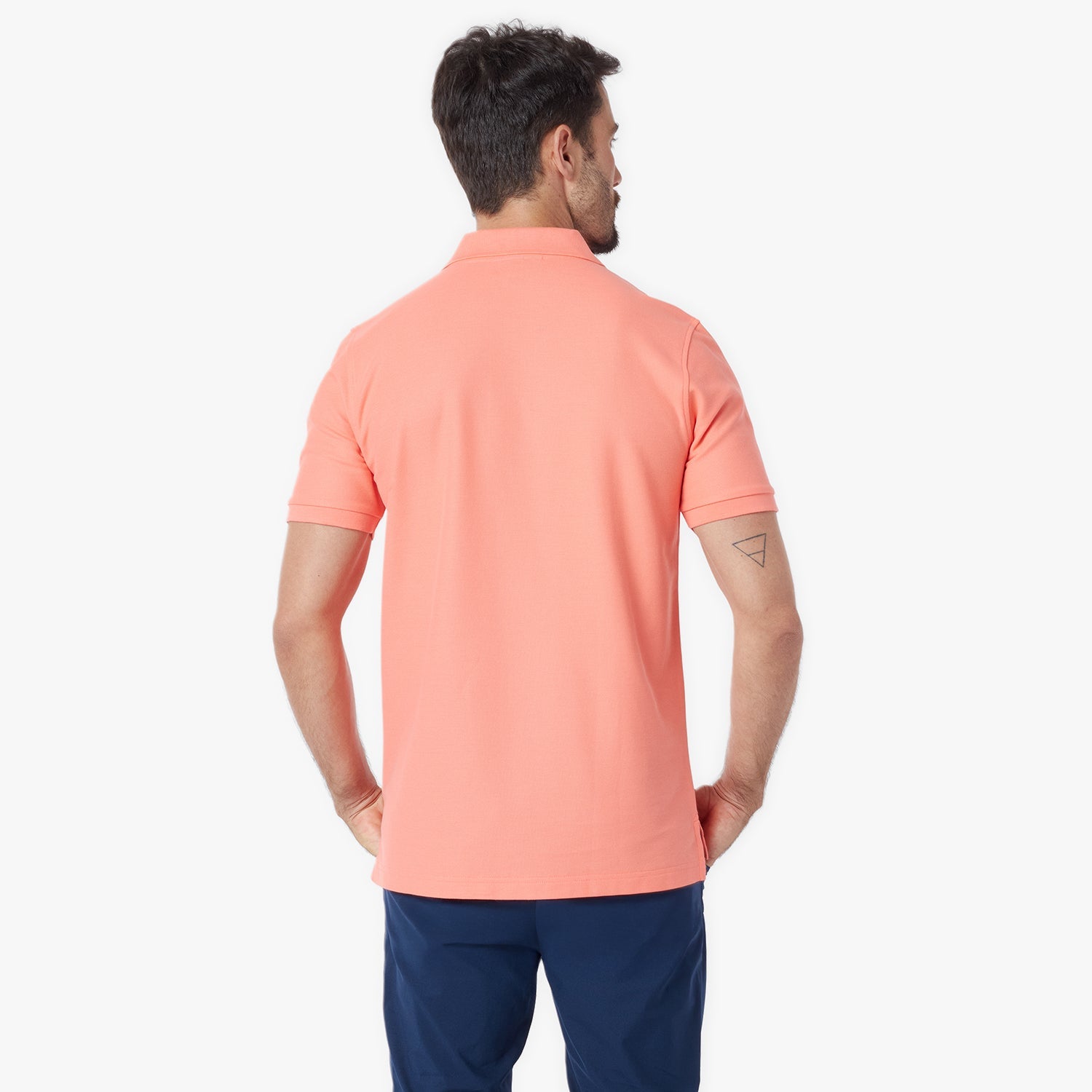Back view of a man wearing a peach-colored polo shirt on a white background