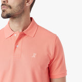 Close-up of a coral polo shirt with a small logo on a white background