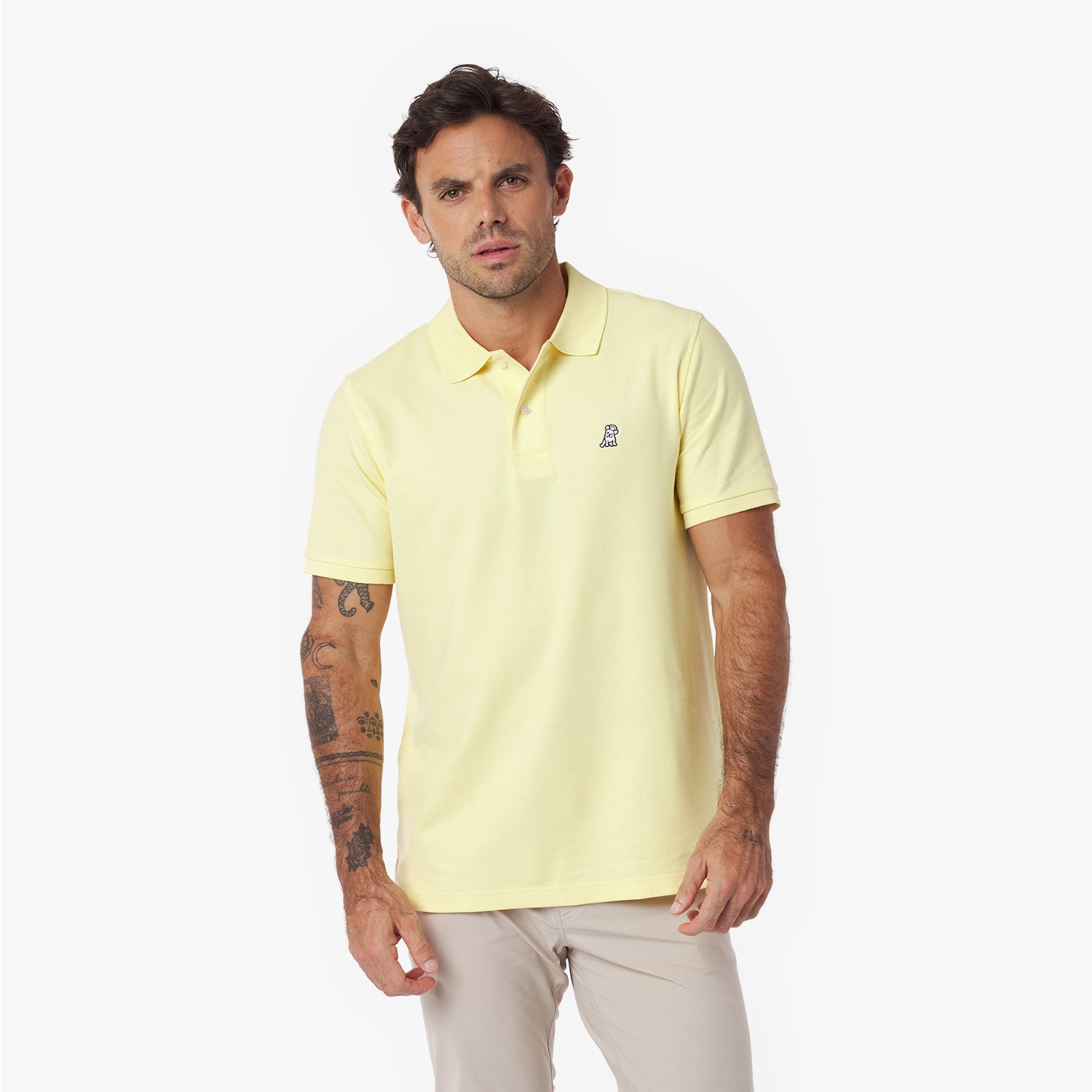 Man wearing a light yellow polo shirt with a small logo on a white background