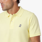 Close-up of a yellow polo shirt with a small logo on a white background