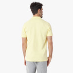 Back view of a man wearing a light yellow polo shirt on a white background