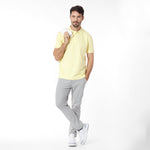 Man wearing a yellow polo shirt and gray pants on a white background