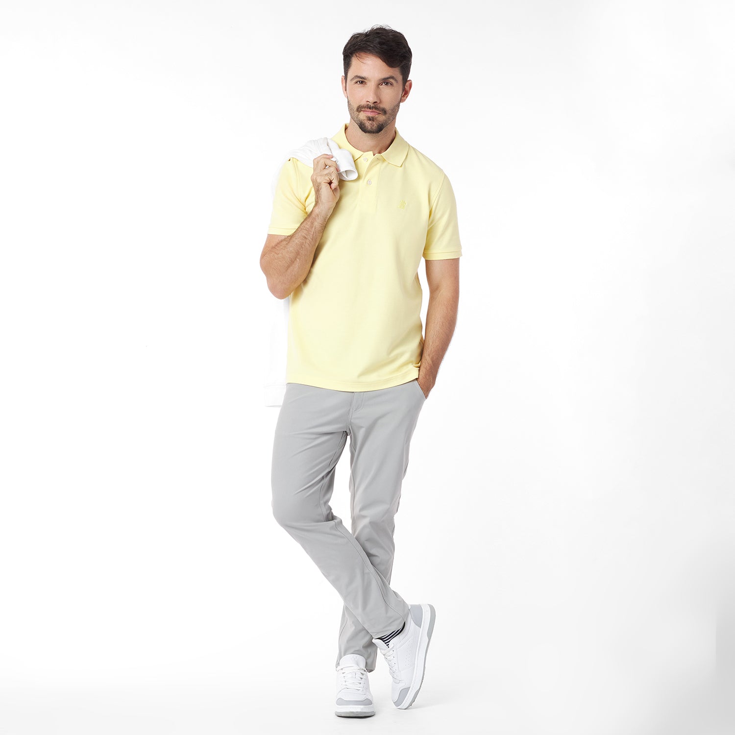 Man wearing a yellow polo shirt and gray pants on a white background
