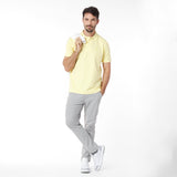 Man wearing a yellow polo shirt and gray pants on a white background