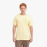 Man wearing a light yellow t-shirt with a small logo on a white background