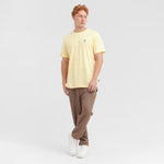 Man wearing a yellow t-shirt and brown pants on a white background