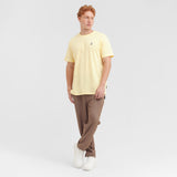 Man wearing a yellow t-shirt and brown pants on a white background