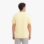 Back view of a man wearing a light yellow t-shirt on a white background