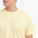 Close-up of a yellow t-shirt with a small logo on a white background