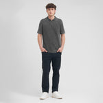 Man wearing a dark gray polo shirt and navy pants on a white background