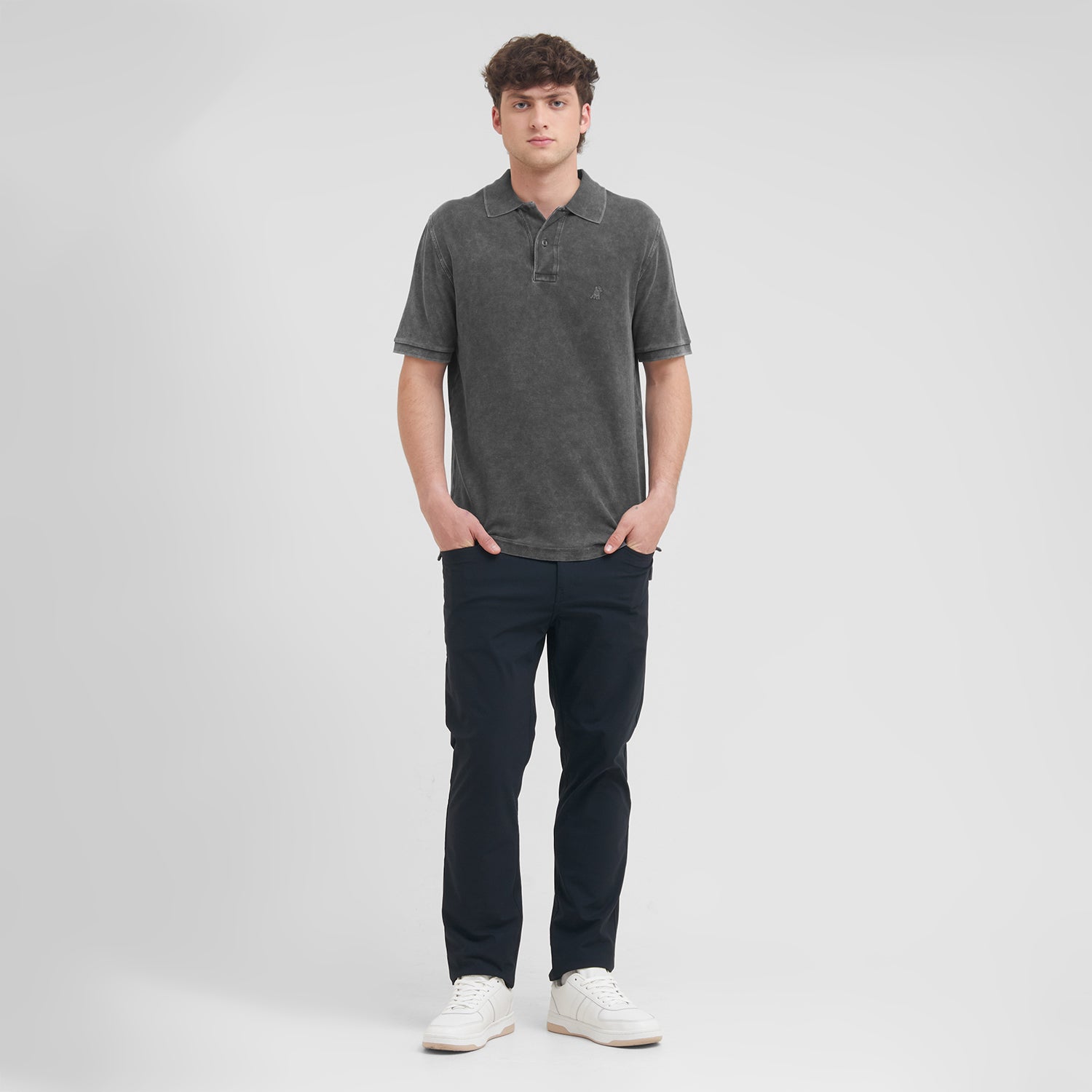 Man wearing a dark gray polo shirt and navy pants on a white background