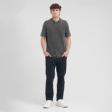 Man wearing a dark gray polo shirt and navy pants on a white background