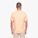 Back view of a man wearing a peach t-shirt on a white background