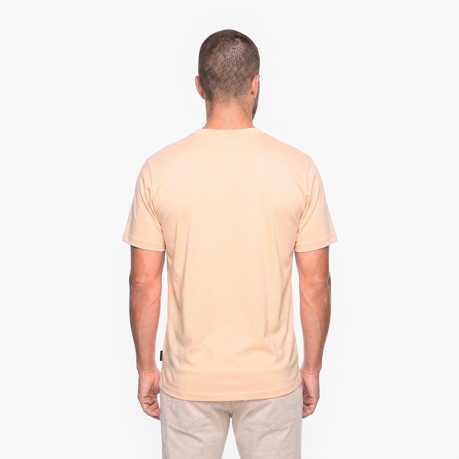 Back view of a man wearing a peach t-shirt on a white background