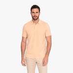 Man wearing a light yellow polo shirt and beige pants on a white background