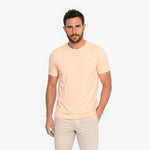 Man wearing a light peach t-shirt and beige pants on a white background