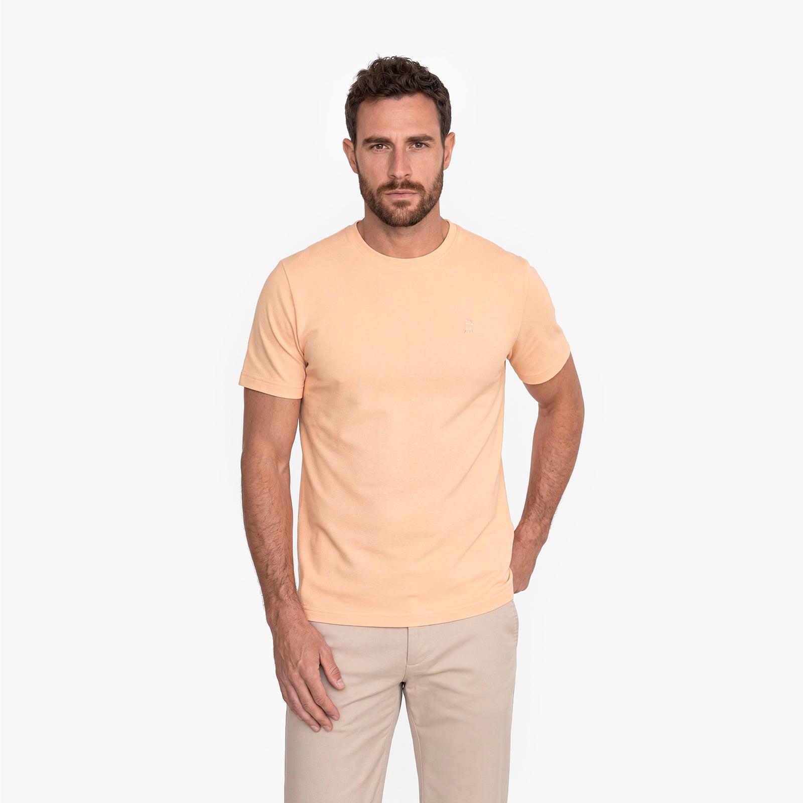 Man wearing a beige t-shirt and pants on a white background