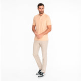 Man wearing a light beige polo shirt and pants on a white background