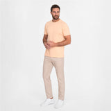 Man wearing a light yellow t-shirt and beige pants on a white background