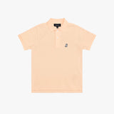 A light peach-pink polo shirt for kids, featuring a small navy embroidered dog logo on the left chest, set against a plain white background.