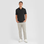 Man wearing a black polo shirt and light gray pants on a white background