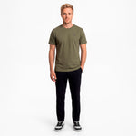 Man wearing a green t-shirt and black pants on a white background