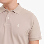 Close-up of a beige polo shirt with a small logo on a white background