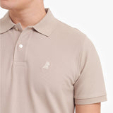 Close-up of a beige polo shirt with a small logo on a white background