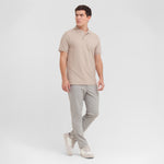 Man wearing a beige polo shirt and gray pants on a white background
