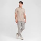 Man wearing a beige polo shirt and gray pants on a white background
