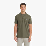 Man wearing a green polo shirt with a small logo on a white background